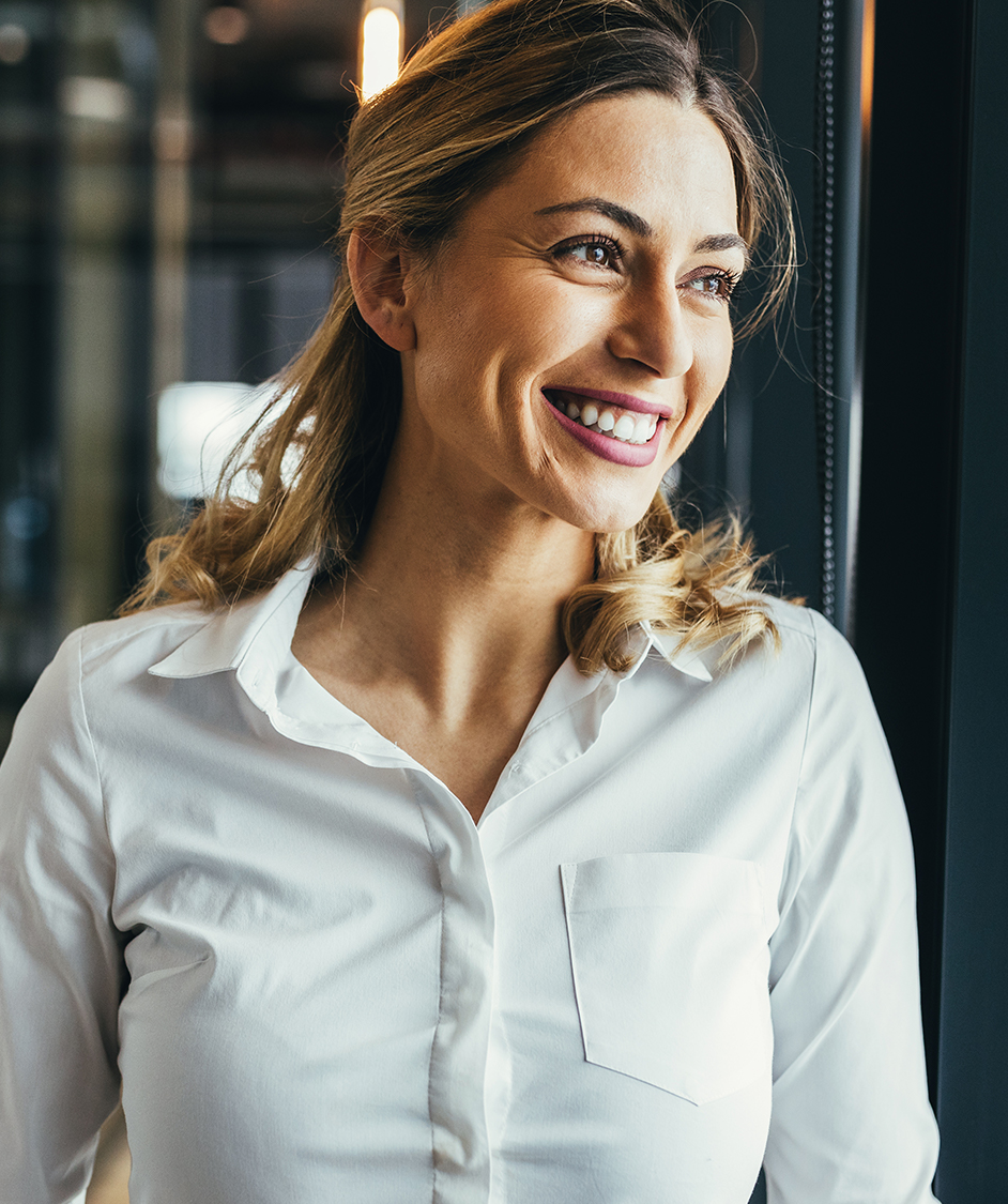 Woman smiling and wearing a white button up long sleeve top