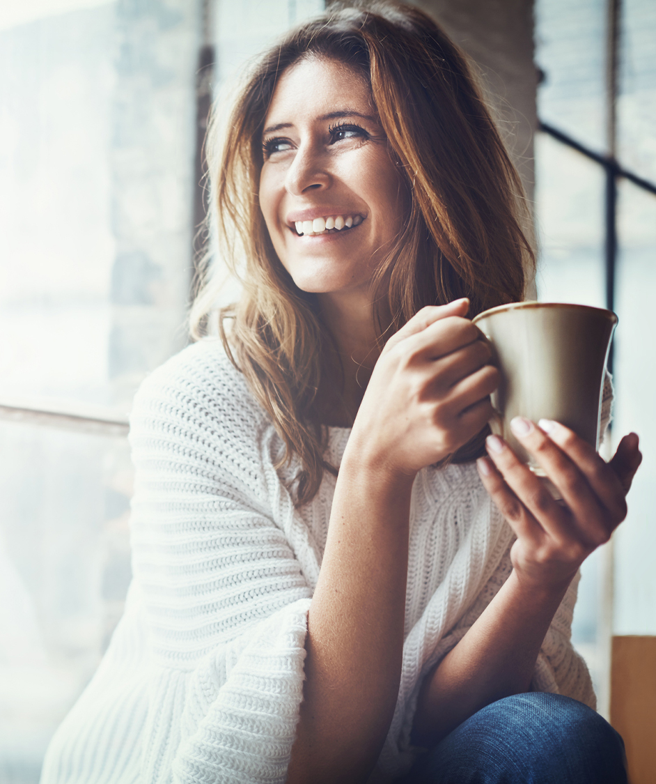 Woman smiling holding a cup of coffee